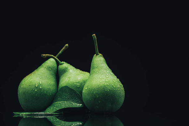 Beautiful fresh pears on a black glass table dark background. - Photo, Image
