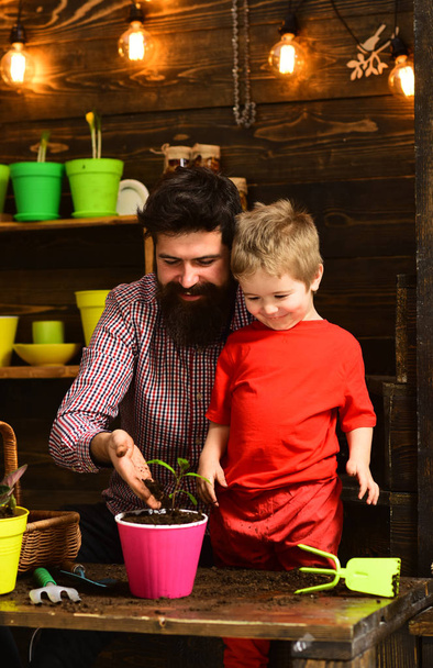 bearded man and little boy child love nature. happy gardeners with spring flowers. Father and son. Fathers day. Flower care watering. Soil fertilizers. Family day. Greenhouse. Natural gift - Foto, afbeelding