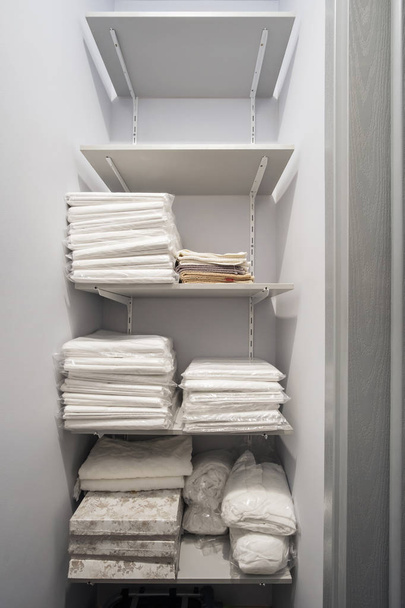  white linens and towels on the shelves - Foto, imagen