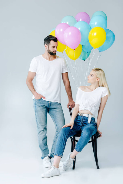 man and beautiful girl on chair near balloons on grey - Foto, Imagem