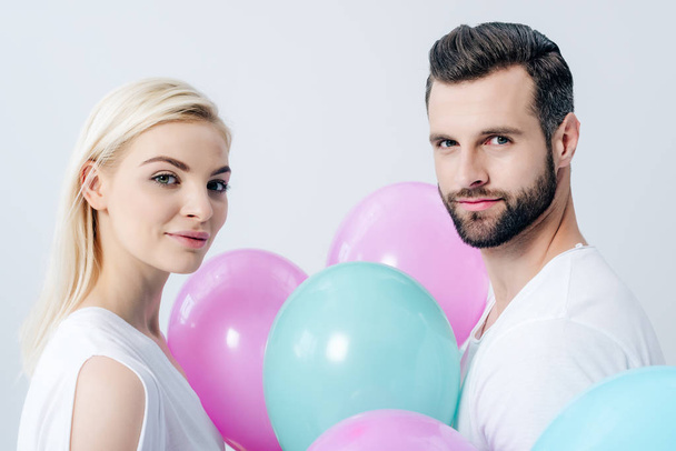 man and beautiful girl with balloons looking at camera isolated on grey - Фото, зображення