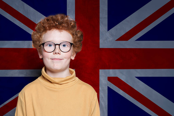 Cute kid student against the UK flag background. Learn English  - Zdjęcie, obraz