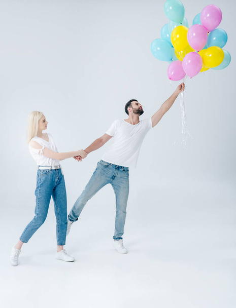 beautiful girl holding hand of man with balloons on grey - Foto, Bild