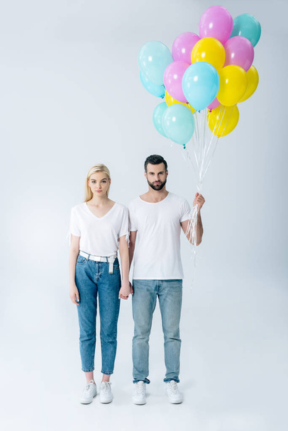 man and beautiful girl with balloons looking at camera on grey - Foto, imagen