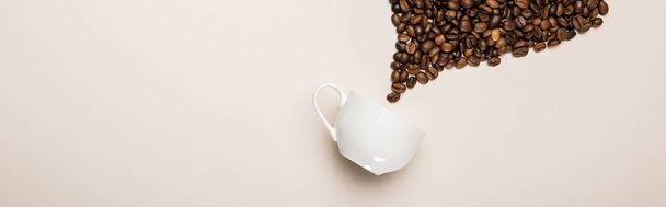 top view of coffee cup near grains on beige background, panoramic shot - Photo, Image
