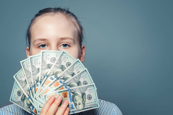 Rich lány gazdaság pénzt készpénz amerikai dollár, kék háttér - Fotó, kép