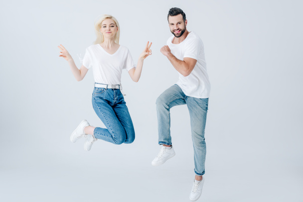 excited man and young woman jumping isolated on grey - Фото, изображение