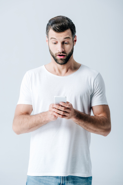 shocked man using smartphone isolated on grey - Fotó, kép
