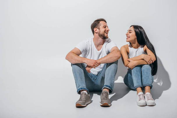 full length view of young couple in love smiling while sitting close to each other  - Foto, afbeelding