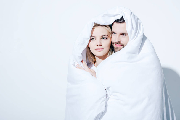 beautiful girlfriend and handsome boyfriend covered in blanket on white - Фото, изображение
