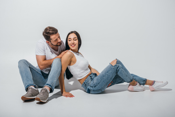 cute couple sitting on floor, smiling and looking at each other - Foto, immagini