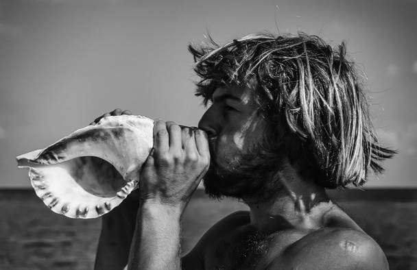 genç adam bir seashell üfleme - Fotoğraf, Görsel