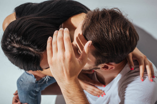 top view of young couple kissing while man hiding faces with hand - Foto, Imagen
