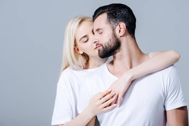 beautiful girl with eyes closed embracing man isolated on grey - Fotografie, Obrázek