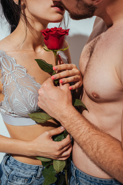 cropped view of couple kissing while holding red rose - Fotografie, Obrázek