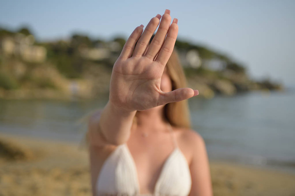 Girl in the beach with his hand raised up in a stop gesture - Photo, Image