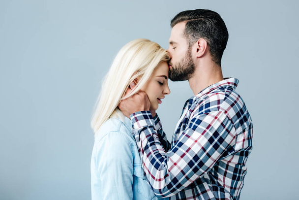 handsome man kissing beautiful young woman isolated on grey - Φωτογραφία, εικόνα
