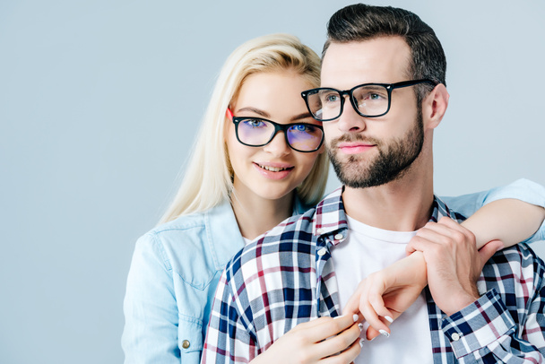 beautiful girl in glasses embracing man isolated on grey - Photo, Image