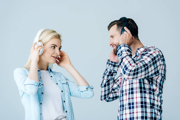 mężczyzna i dziewczynka w słuchawkach patrząc na siebie izolowane na szarym - Zdjęcie, obraz