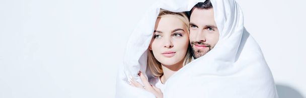 panoramic shot of girlfriend and boyfriend covered in blanket looking away on white - Fotoğraf, Görsel