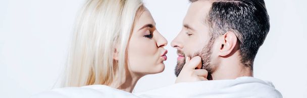 tiro panorâmico da namorada amamentando lábios perto namorado coberto de cobertor no branco
 - Foto, Imagem