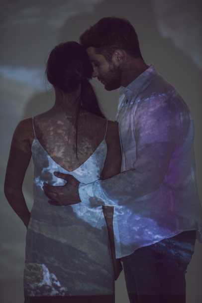 joven hombre abrazando novia mientras de pie en lugar oscuro
 - Foto, imagen