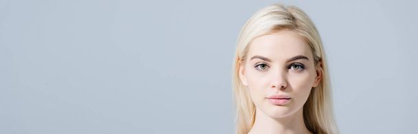 panoramic shot of beautiful blonde girl looking at camera isolated on grey with copy space - Фото, изображение