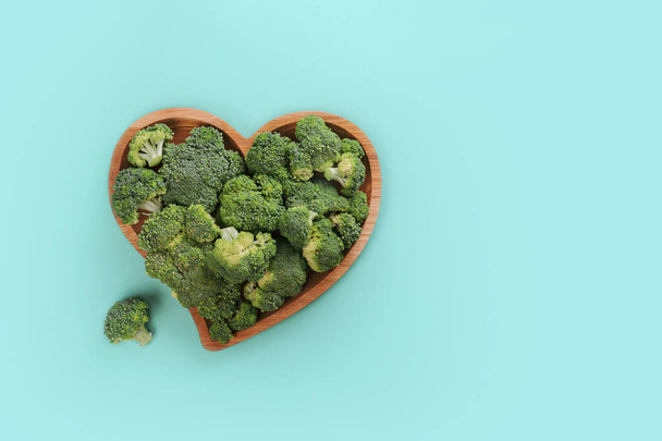 Καρδιά σε σχήμα φρέσκου πράσινου μπρόκολου σε ξύλινη πλάκα που απομονώνεται σε λευκό. - Φωτογραφία, εικόνα