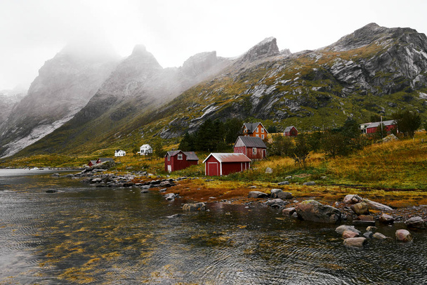 ノルウェーのロフォーテン諸島を背景に山々が立つヴィンスタッドの海岸にある遠く離れた古い漁村のパノラマビュー. - 写真・画像