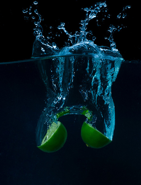 The lime slices falling into the water . - Foto, afbeelding