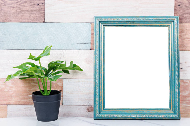 Blank vintage photo frame on wooden wall with plant. - Valokuva, kuva