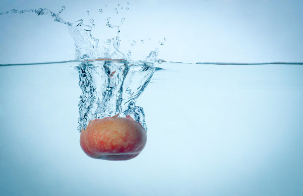 Peach drop in blue water with splashes - Foto, Imagem