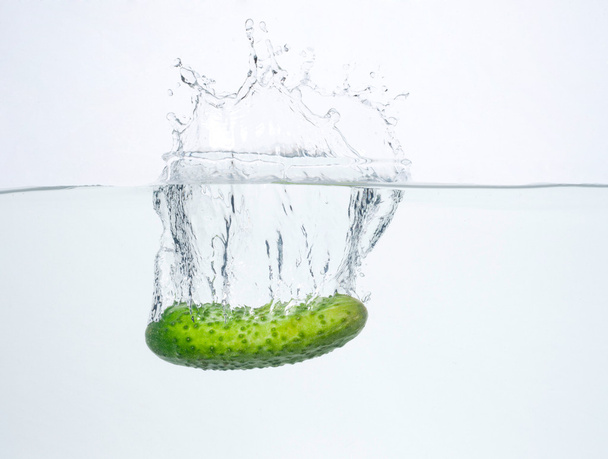 Green cucumber dropped into water isolated on white - Foto, afbeelding