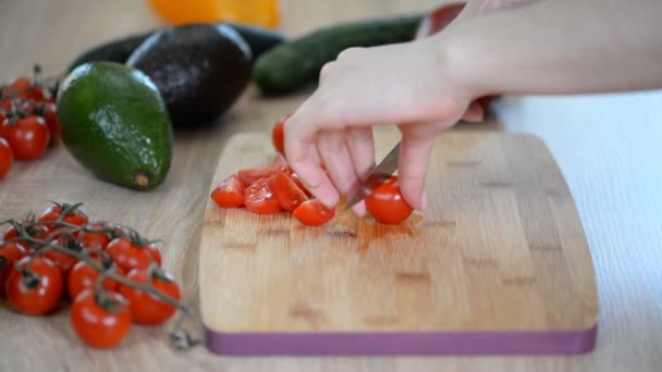 Mujer está cortando tomates cherry para la ensalada en la mesa de madera
. - Imágenes, Vídeo
