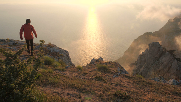 Силуэт юношеских рук простирается, наблюдая красивый красочный закат над морем с высокой горы в Крыму
. - Кадры, видео