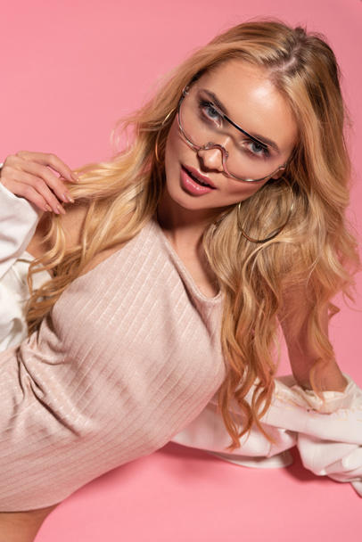 красивая блондинка в телесном костюме и солнцезащитных очках позирует изолированно на розовый
 - Фото, изображение