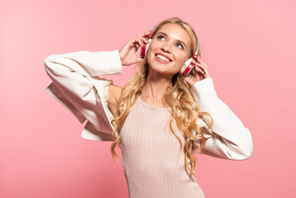 belle blonde rêveuse femme heureuse écoutant de la musique dans des écouteurs isolés sur rose
 - Photo, image