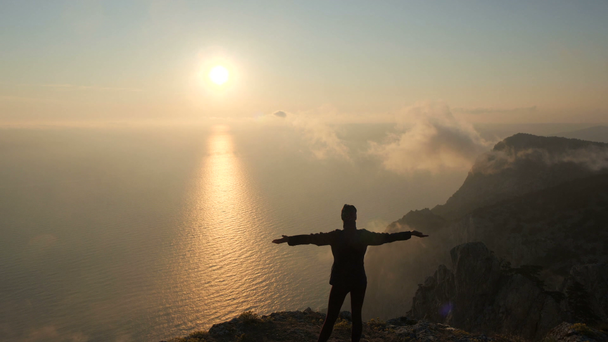 Silhuette junge Frau Arme ausgestreckt beobachten einen schönen dramatischen Sonnenuntergang über einem Meer von einem hohen Berg in Krim. - Filmmaterial, Video