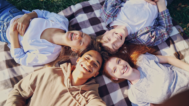 Groupe d'étudiants multiethniques heureux s'amuser ensemble et faire du selfie tout en étant couché à l'extérieur dans le parc
 - Séquence, vidéo