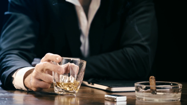küllük ve viski sallayarak cam puro ile ahşap masada oturan işadamı kırpılmış görünümü - Video, Çekim