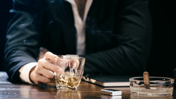 küllük ve viski sallayarak cam puro ile ahşap masada oturan işadamı kırpılmış görünümü - Video, Çekim