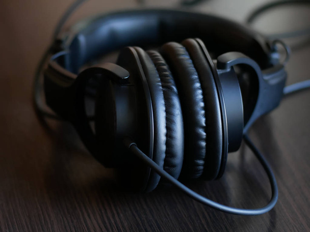 schwarze Studiokopfhörer auf einem schwarzen Holztisch. Kopfhörer für Sounddesigner - Foto, Bild