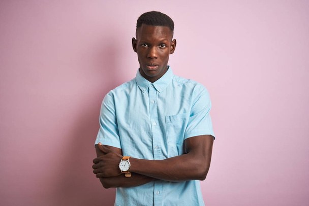 African american man wearing blue casual shirt standing over isolated pink background skeptic and nervous, disapproving expression on face with crossed arms. Negative person. - Photo, Image