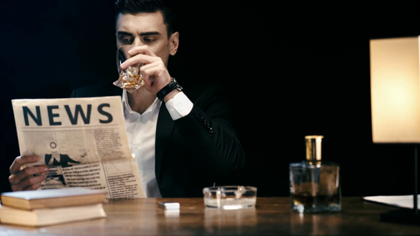 konzentrierter Geschäftsmann liest Zeitung und hält Feuerzeug am Tisch auf schwarz - Filmmaterial, Video
