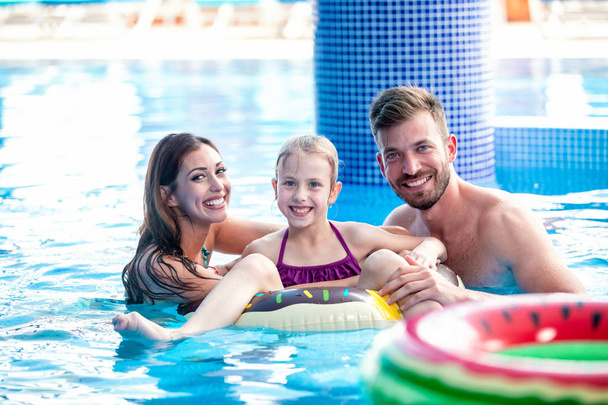 Happy couple enjoying their time in the pool with their daughter - Fotografie, Obrázek