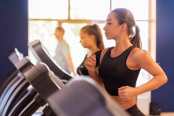 Close up young fit women on modern treadmill in gym - Photo, Image