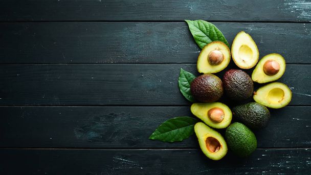Fresh avocado with leaves on a black background. Top view. Free space for your text. - Foto, Bild
