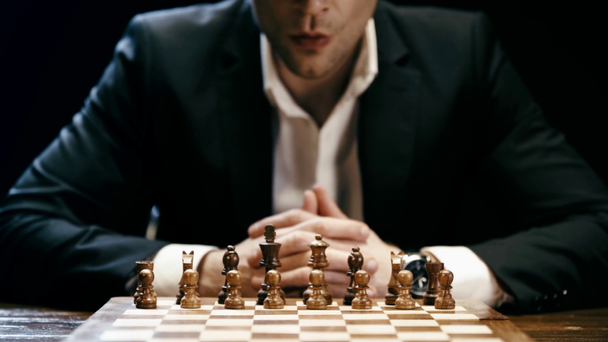 частичный взгляд сфокусированного бизнесмена, сидящего за столом, играющего в шахматы и потереющего нос
 - Кадры, видео