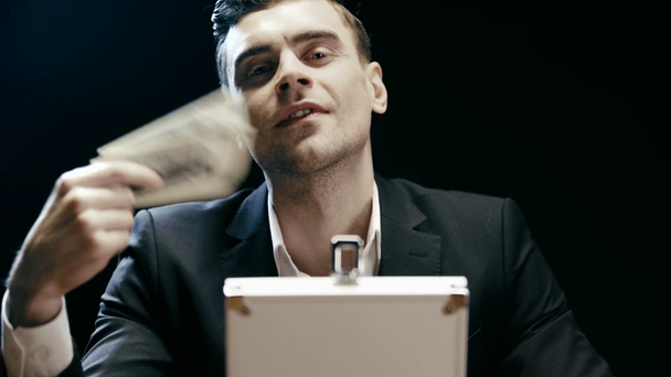 vista frontal del hombre de negocios satisfecho con maletín con billetes de dólar y sonriendo en negro
 - Metraje, vídeo