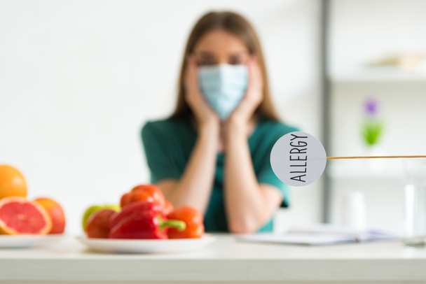 selective focus of woman in medical mask propping face with hands and nameplate with inscription allergy - Photo, Image